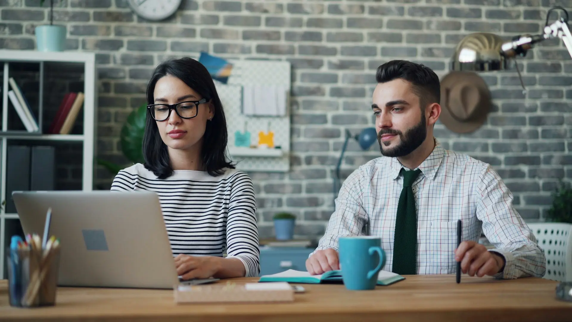 a man and a woman sitting at a table with a laptop