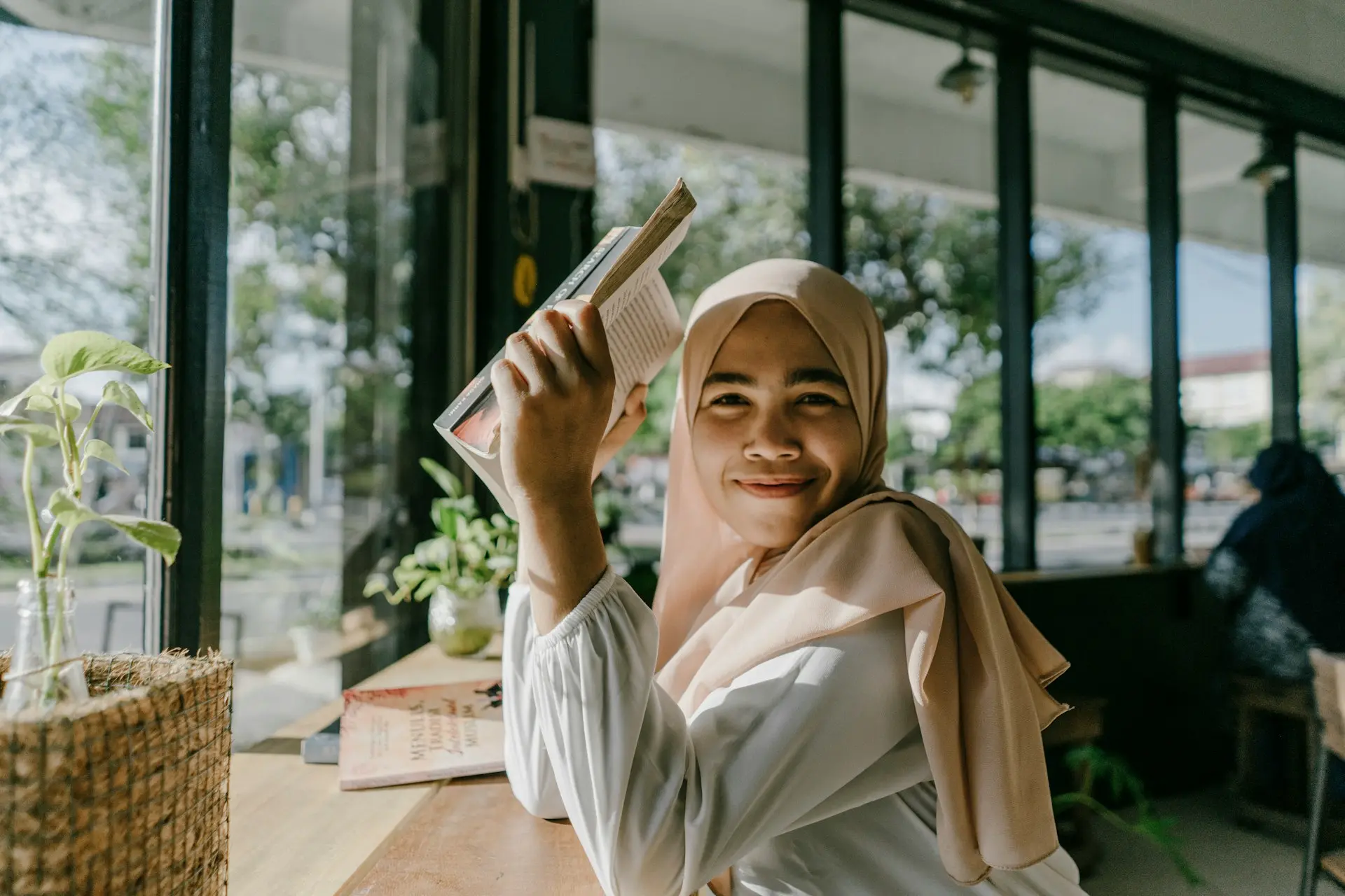 a woman in a hijab is holding a book